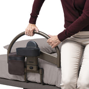 Person using a bed rail with a cup holder on a bed