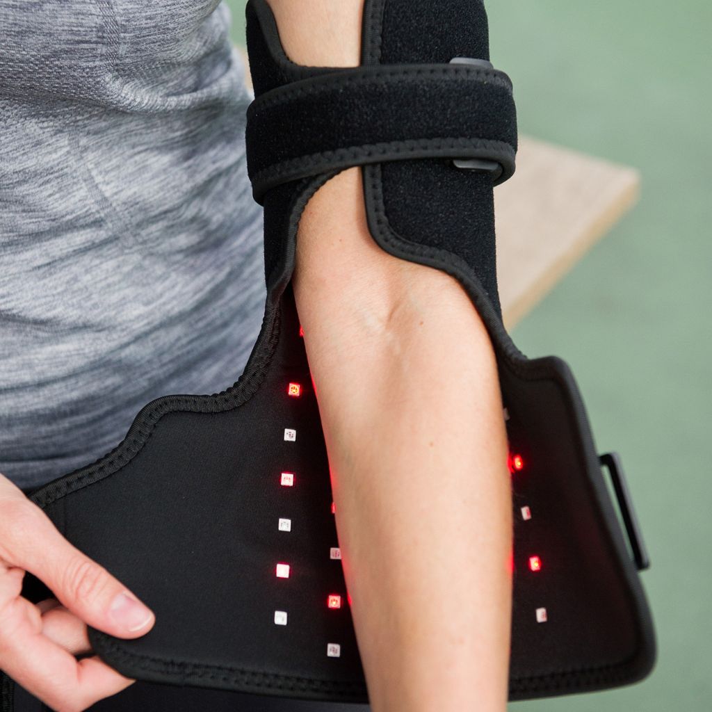Person wearing a black arm brace with LED lights on a green background