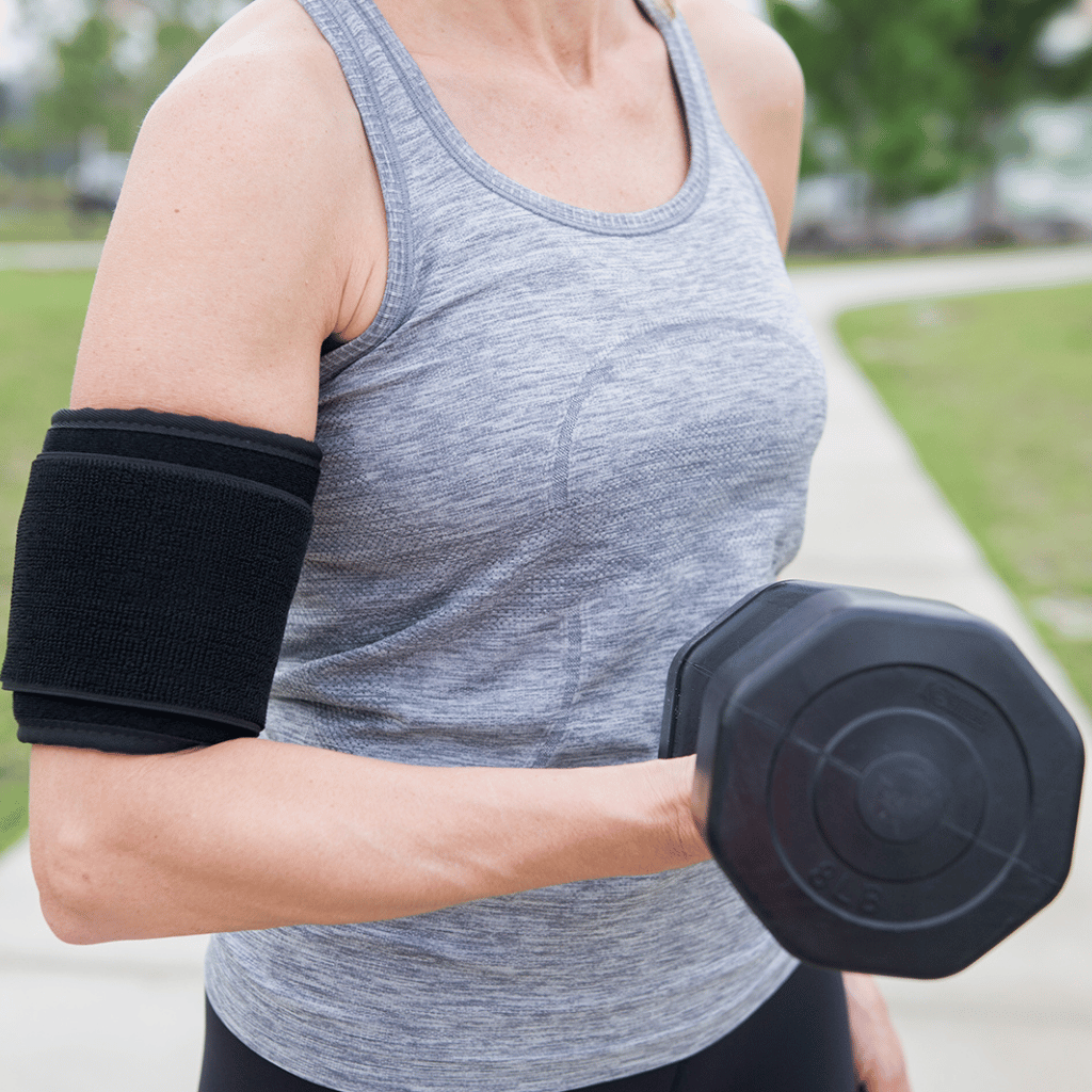 Person exercising with a black dumbbell outdoors while wearing the dpl® Back and Body Flex Pad
