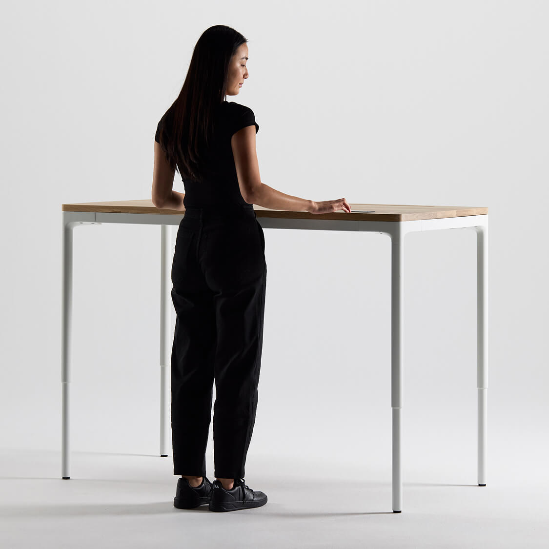 Woman standing at a modern standing desk with a minimalist design.