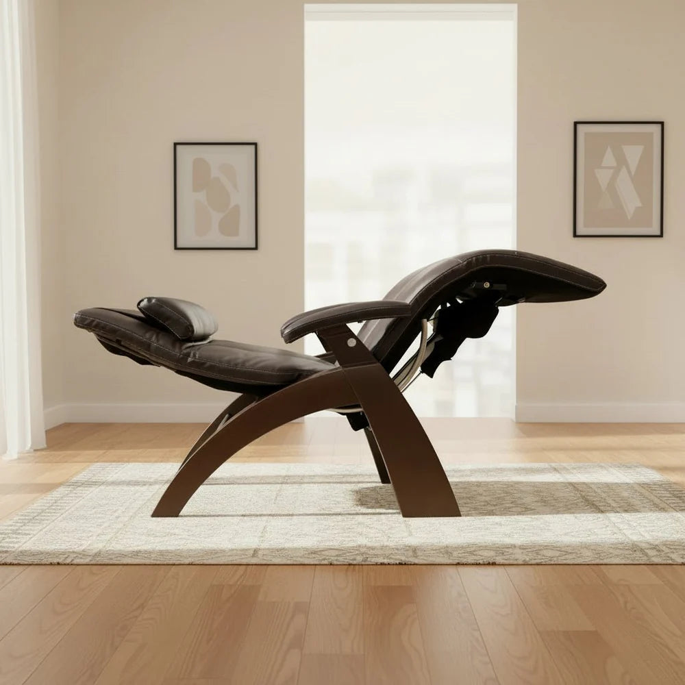 Dark brown leather recliner with a curved wooden frame, fully reclined in a bright minimalist living room with light wood floors and soft natural light.
