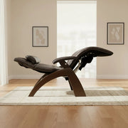 Dark brown leather recliner with a curved wooden frame, fully reclined in a bright minimalist living room with light wood floors and soft natural light.