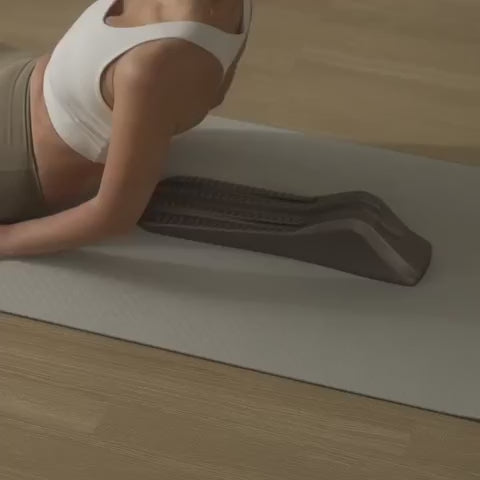 Load video: Woman using a gray spine decompression stretcher on her back