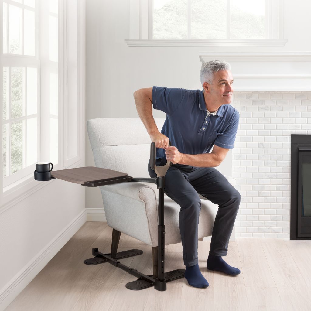 Man using a tray with a standing assistance handle in a home setting