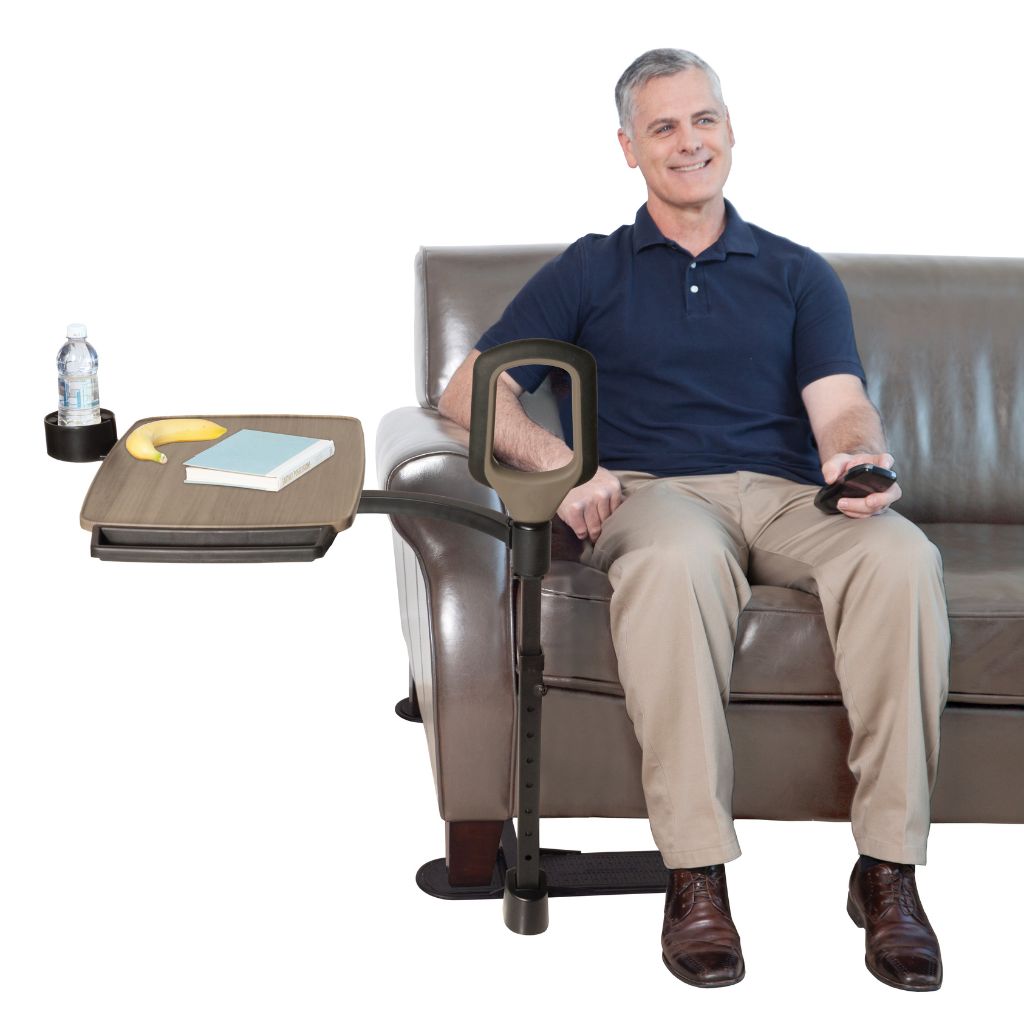 Man sitting on a couch with a adjustable armrest and tray attached, holding a remote control.