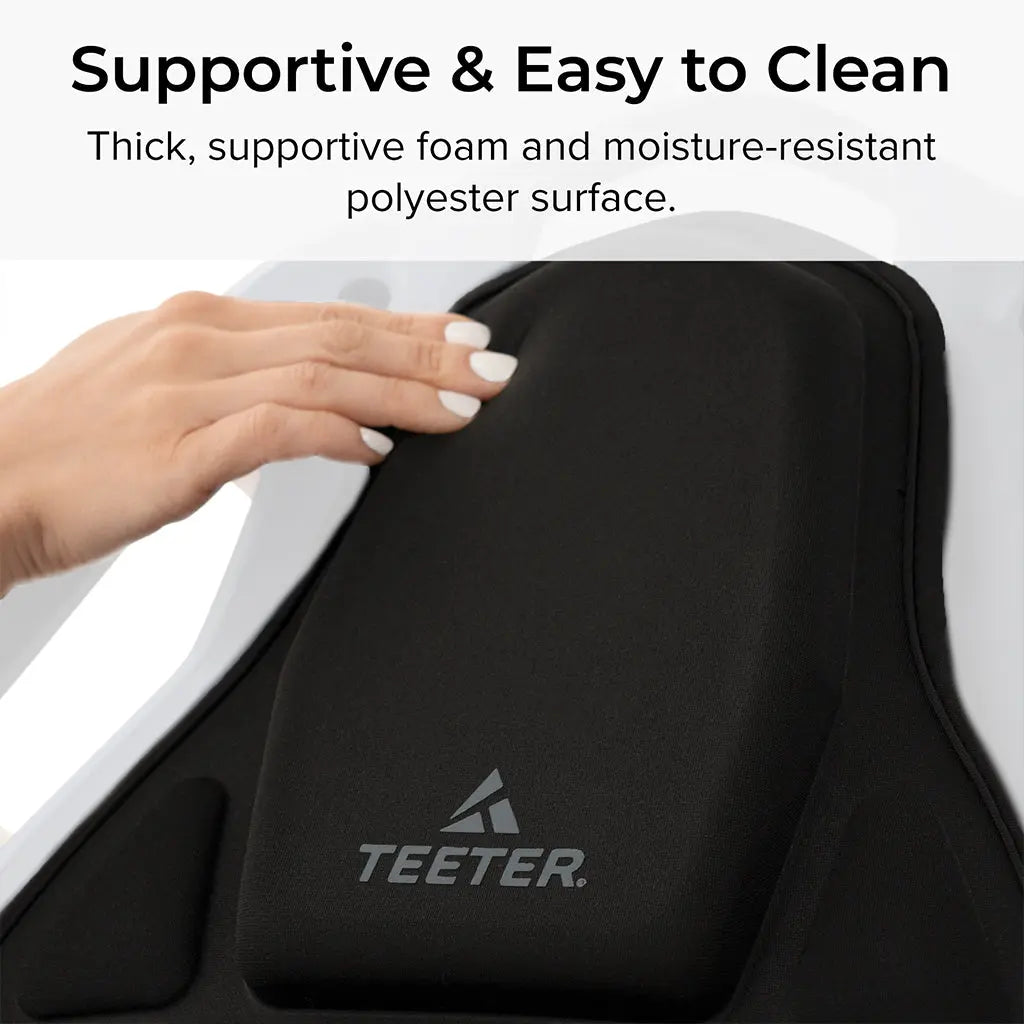 Close-up of the FitSpine Heat and Vibration Comfort Cushion by Teeter, featuring a black inversion table cushion. The text highlights its "Supportive and Easy to Clean" design, showcasing thick foam for comfort and a moisture-resistant polyester surface.