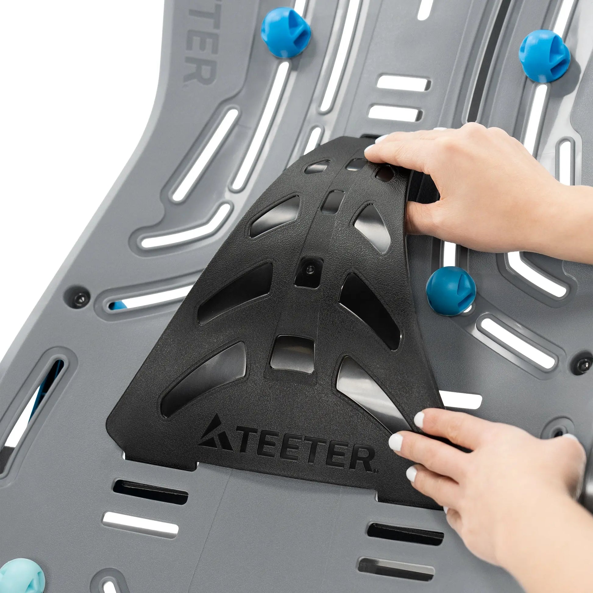 A woman attaching the lumbar extender to the Teeter Fitspine XC5 Inversion Table.