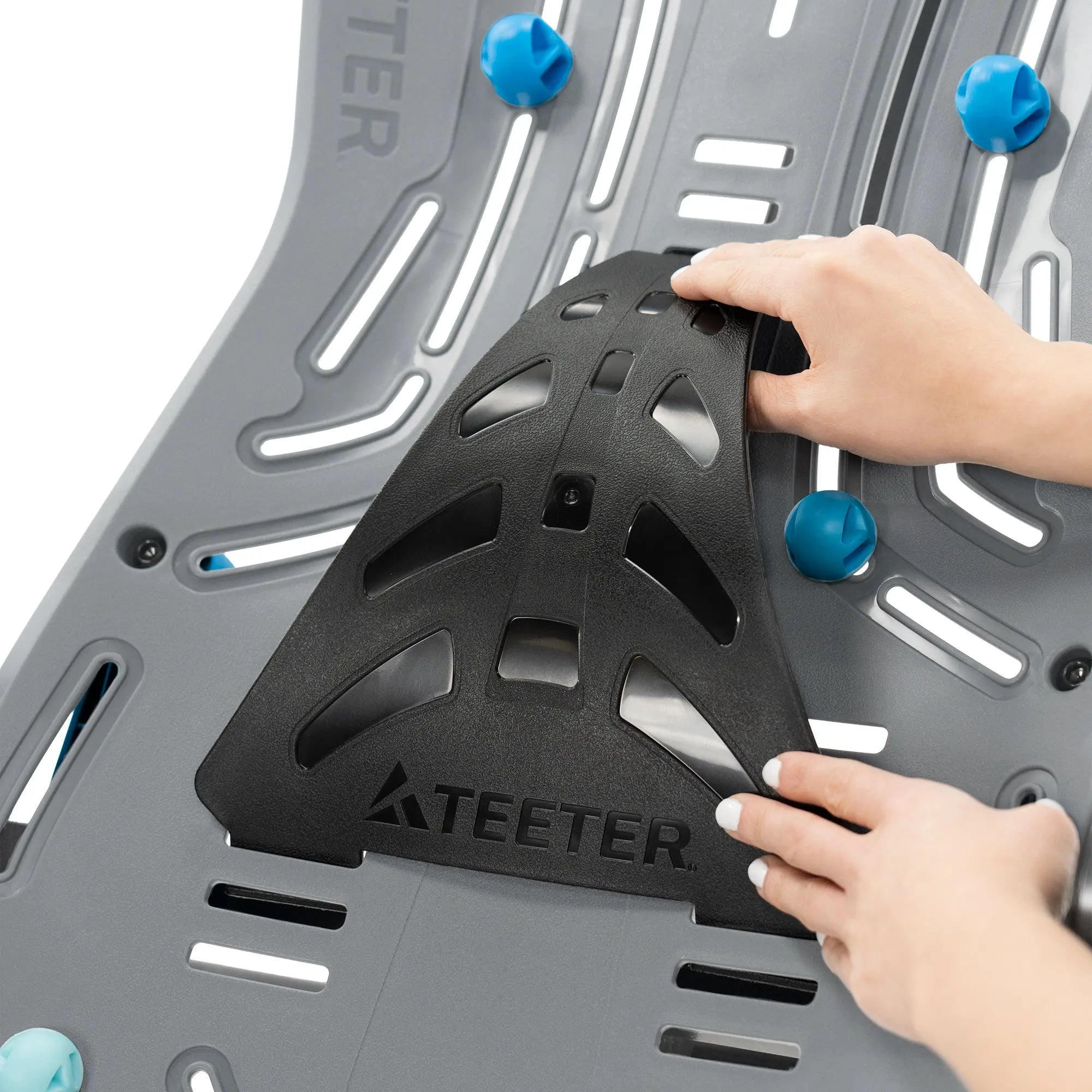 A woman attaching the lumbar extender to the Teeter Fitspine XC5 Inversion Table.