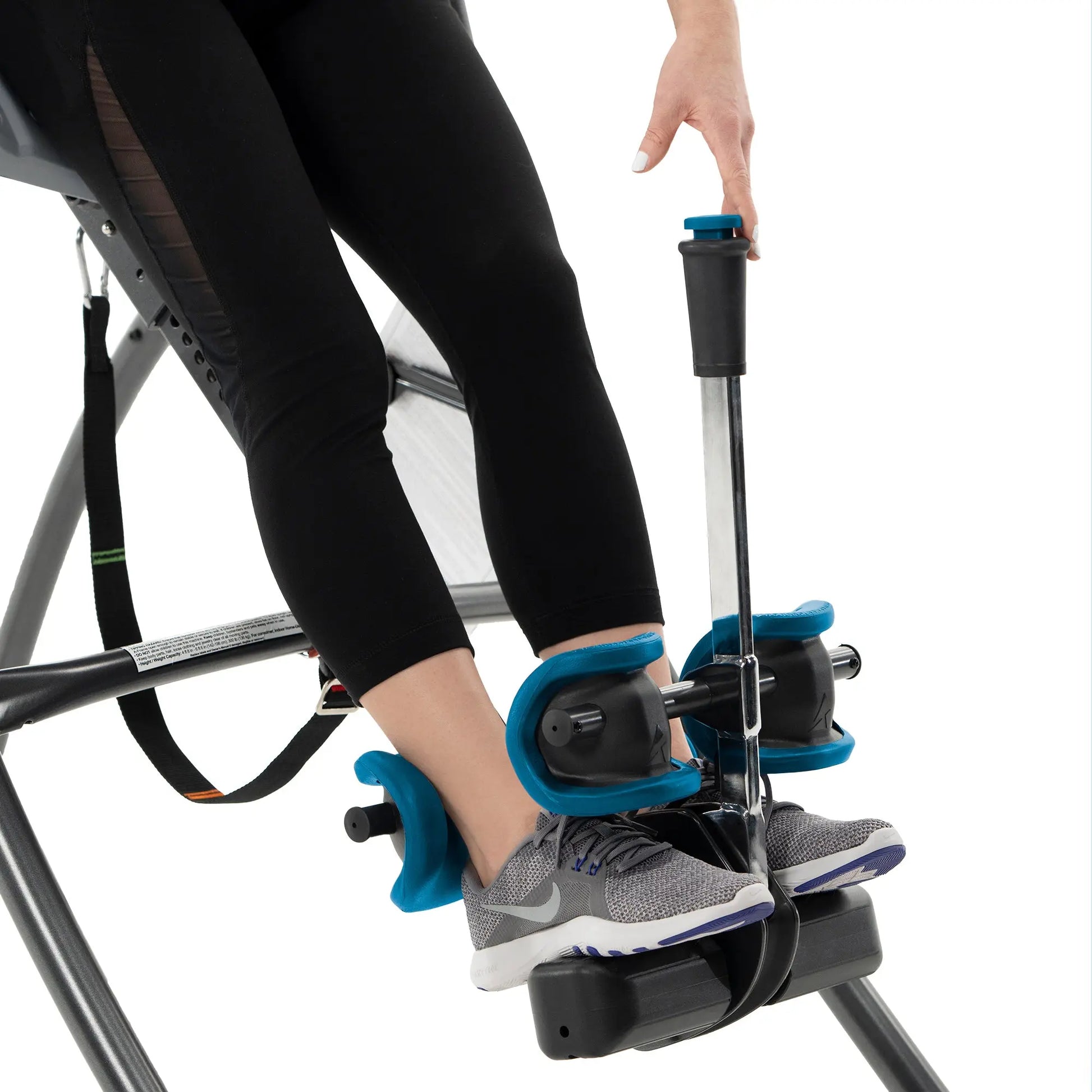A person's feet are positioned on the Fitspine XC5 Inversion Table by Teeter, highlighting the ankle locking mechanism against a white backdrop..