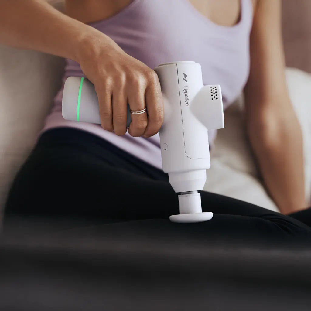 A woman using the Hypervolt Go 2 Percussion Handheld Massager on her leg